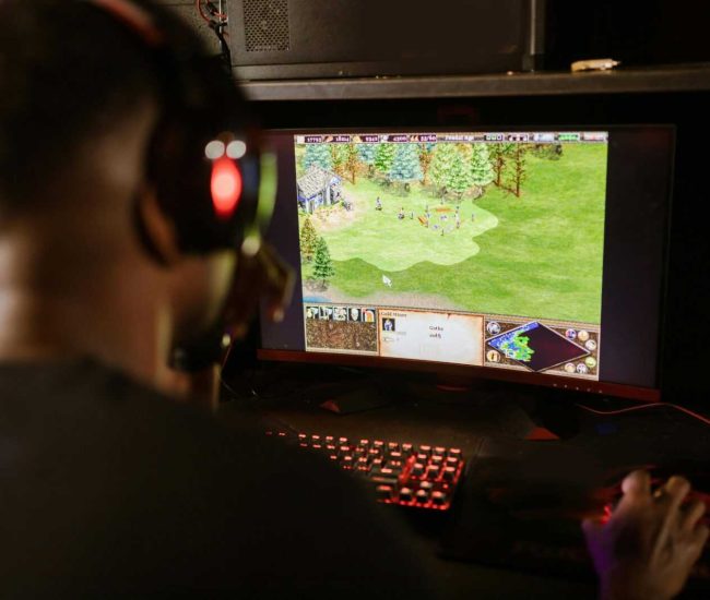 A gamer intensely playing a strategy game on a high-resolution monitor indoors.
