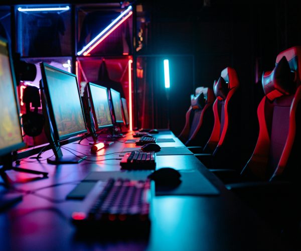An immersive gaming room with neon lights, computers, and gaming chairs ready for a tournament.