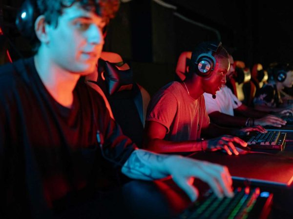 Young gamers competing in a gaming tournament, using headsets and keyboards with focused expressions.
