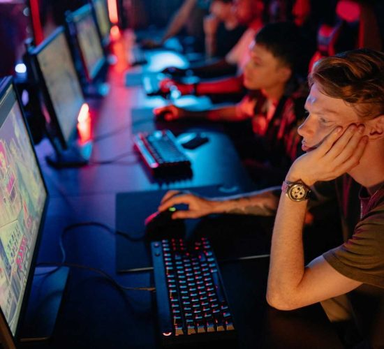 Gamers intensely focused on a computer game during an online esport competition in a dimly lit arena.